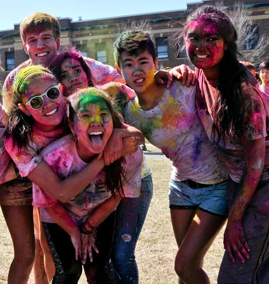 Group of smiling students covered in colorful powder