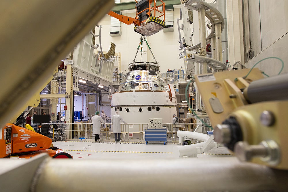 A crane returns NASA’s Artemis II Orion spacecraft to the Final Assembly and System Testing (FAST) cell inside the Neil A. Armstrong Operations and Checkout Building at NASA’s Kennedy Space Center