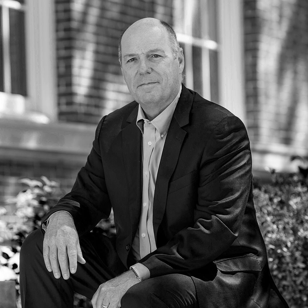 A black and white portrait of Martin A. Schmidt sitting outside on campus.