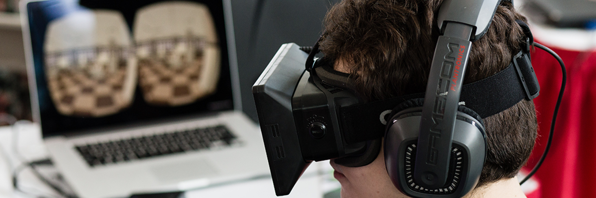 Gaming student with virtual headset works at laptop