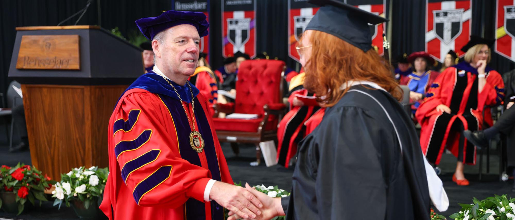 President Schmidt shakes hands with a graduate