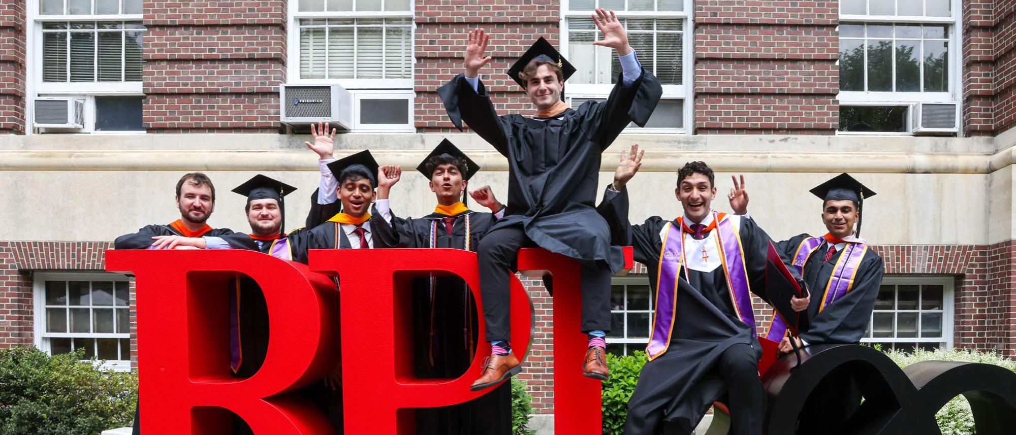 RPI graduates pose on RPI Bicentennial logo