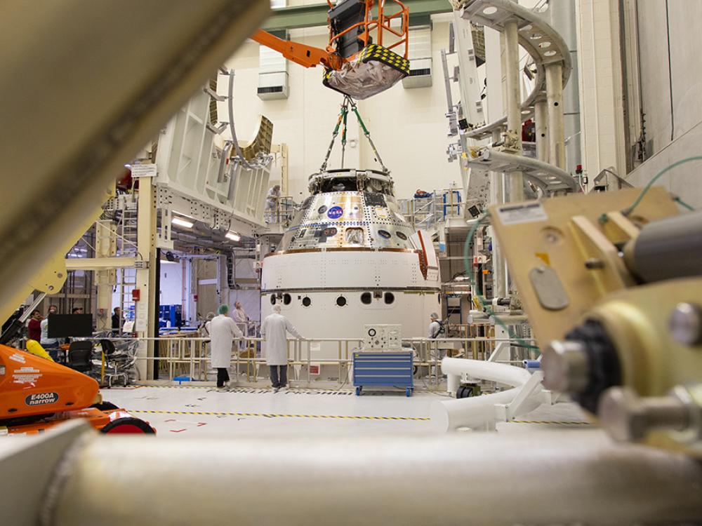 A crane returns NASA’s Artemis II Orion spacecraft to the Final Assembly and System Testing (FAST) cell inside the Neil A. Armstrong Operations and Checkout Building at NASA’s Kennedy Space Center