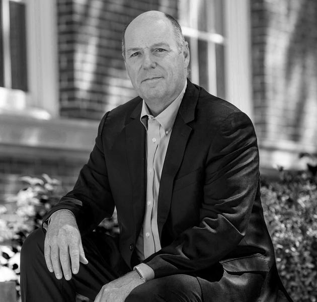 A black and white portrait of Martin A. Schmidt sitting outside on campus.