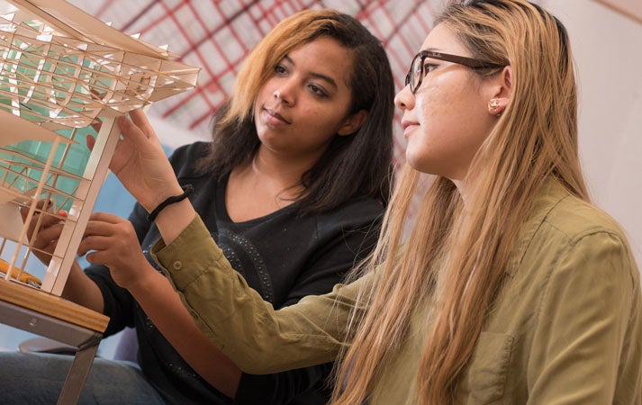 Two students examining a wooden model